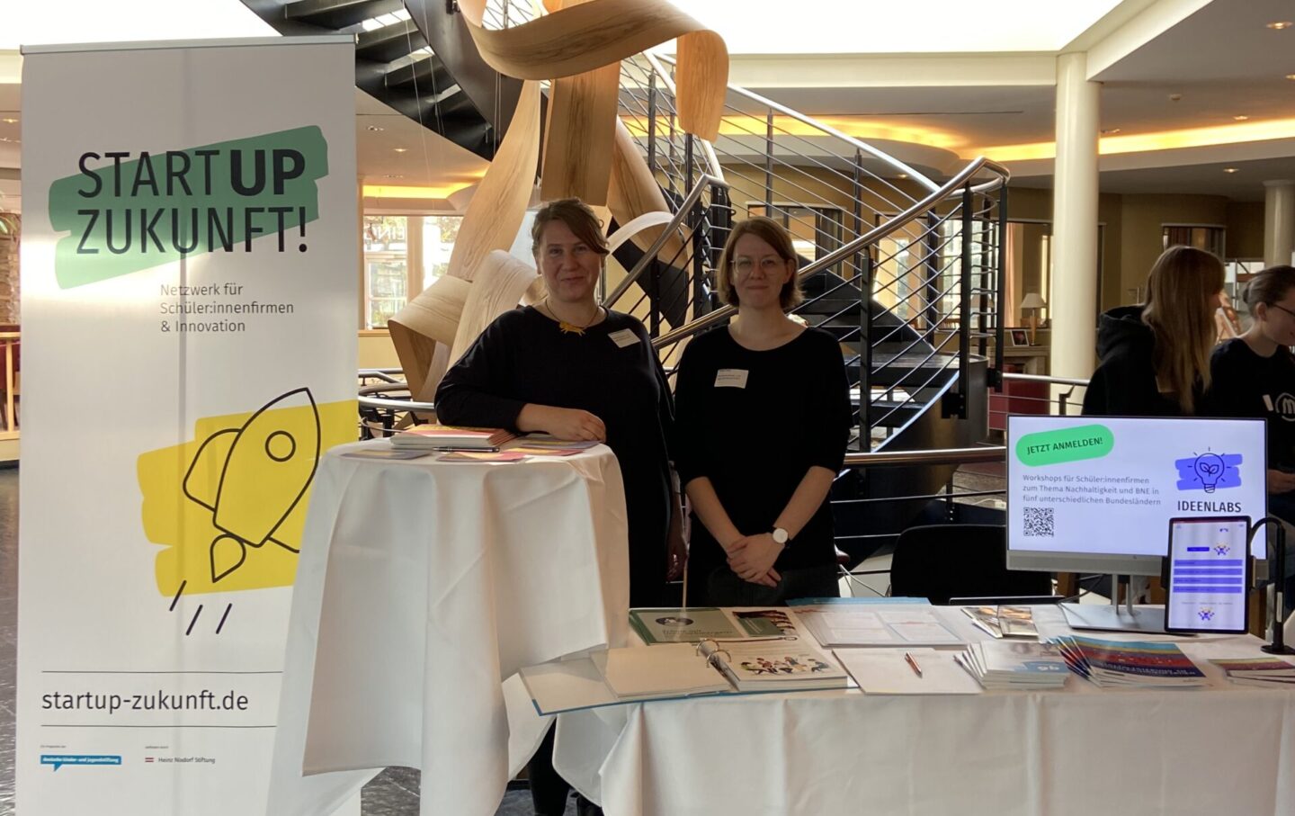 Zwei Frauen stehen an einem Messestand von Startup Zukunft.